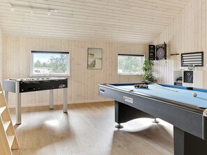 A room with a foosball table, a pool table, and windows with views of trees. - 5 Star Holiday Home in Idestrup (Idestrup)