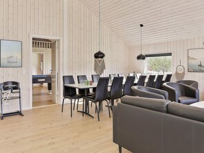 Un interior moderno con zona de comedor, un sofá y vistas a través de una puerta.