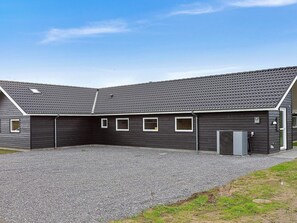 A modern building with a dark exterior, a sloped roof, and a gravel driveway. - 5 Star Holiday Home in Idestrup (Idestrup)