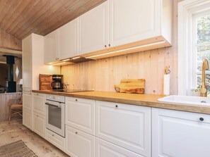 A modern kitchen with white cabinetry, a wooden countertop, and a built-in oven.