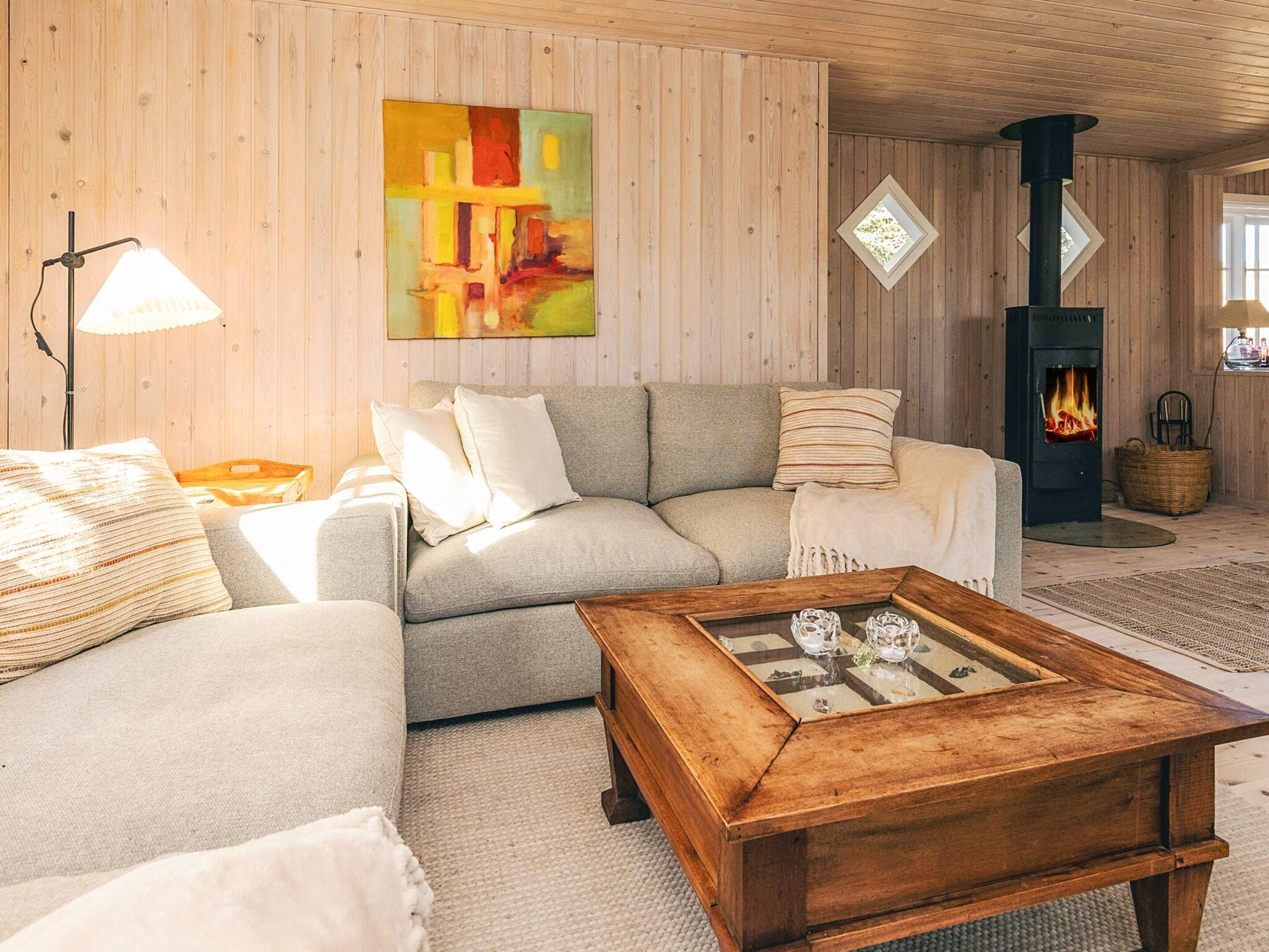 A cozy living room with a sofa, a coffee table, a fireplace, and a painting on the wall.