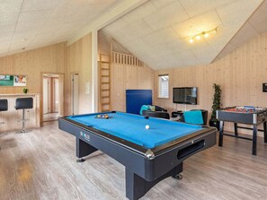 A pool table with a blue felt surface, a foosball table, and a television mounted on the wall. - 5 Star Holiday Home in Albaek (Aalbaek)