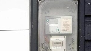 Medidor de servicios con una etiqueta y pantalla digital, montado sobre una estructura metálica.