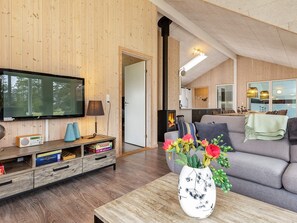 A cozy living room with a television, a fireplace, a sofa, and a coffee table with a vase of flowers. - 5 Star Holiday Home in Albaek (Aalbaek)