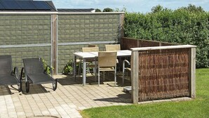 Une terrasse extérieure avec une table et des chaises, un espace salon couvert et un panneau solaire sur le toit.