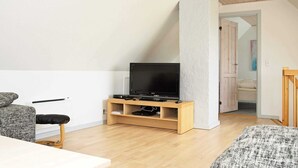 Un salon moderne avec un meuble TV en bois, un canapé et une table à manger.