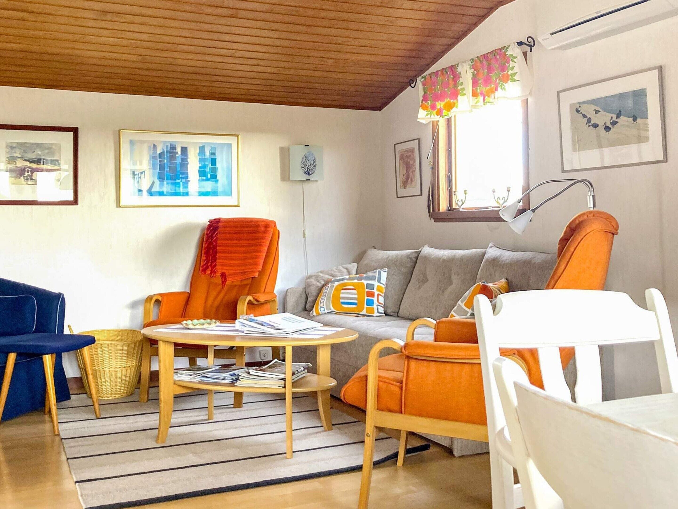 Ett vardagsrum med en soffa, fåtöljer, ett soffbord och ett fönster med gardiner.