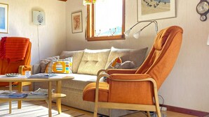 A living room with a sofa, a wooden coffee table, a high-back chair, and a lamp. - 4 Person Holiday Home in Falkenberg (Falkenberg)