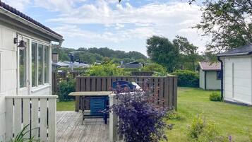 A residential property with a deck, a fenced garden, and a house with a sloped roof.