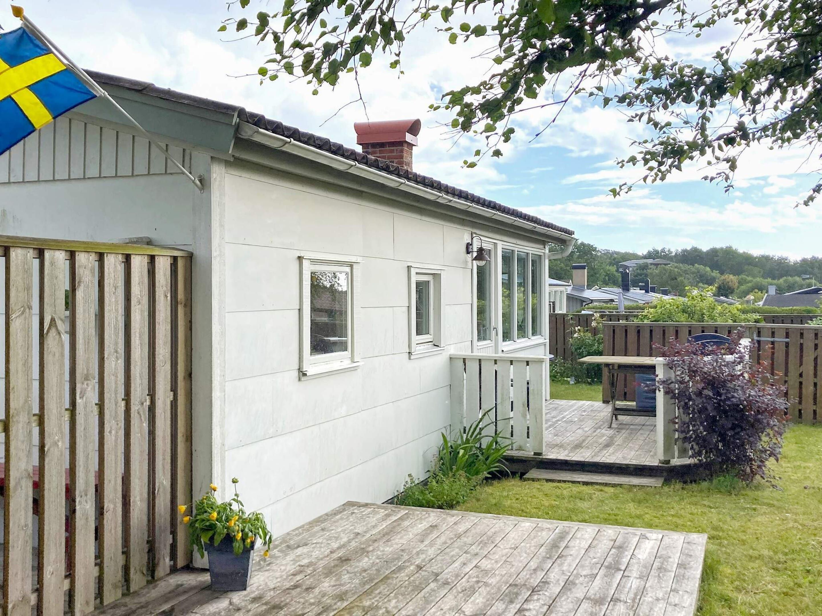 Ett envåningshus med vit fasad, en träveranda och en flagga.