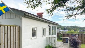 A single-story house with a white exterior, a wooden deck, and a flag. - 4 Person Holiday Home in Falkenberg (Falkenberg)
