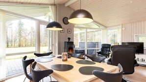 A modern living room with a wooden dining table, black chairs, a fireplace, and a TV. - 6 Person Holiday Home in Hojslev-by Traum (Hojslev)