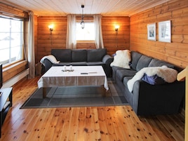 Interior acogedor de una cabaña de madera con un conjunto de sofás, una mesa de centro y una chimenea.