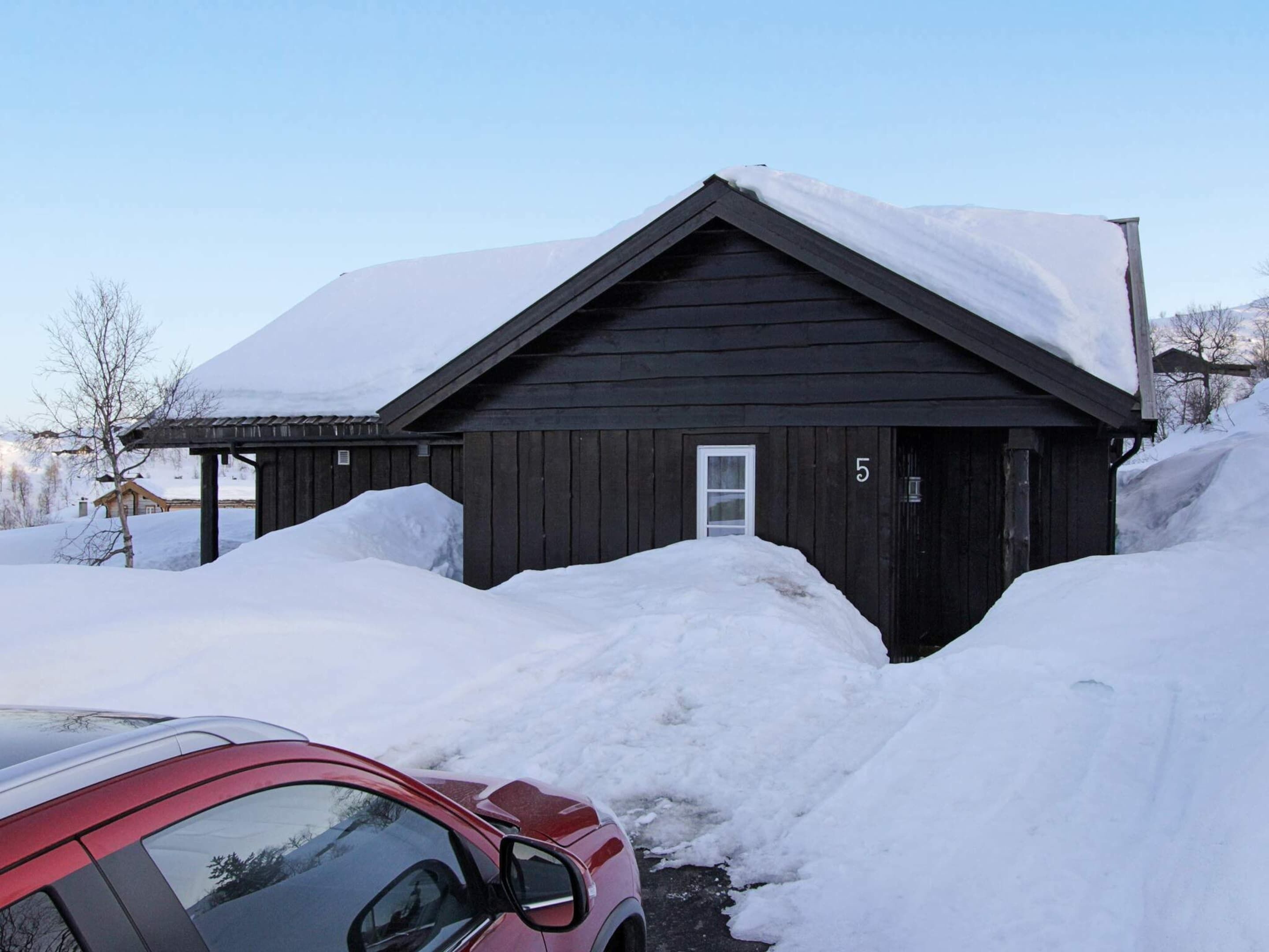 A wooden cabin with a number '5' on the door, surrounded by snow.