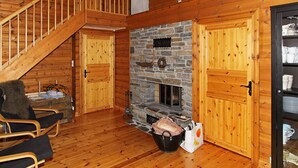 A wooden cabin interior with a stone fireplace, wooden doors, and a staircase. - 10 Person Holiday Home in Aseral (Aseral)