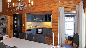 A cozy cabin interior with a dining area, kitchen, and a fireplace. - 10 Person Holiday Home in Aseral (Aseral)