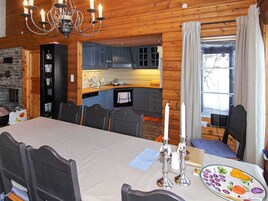 Interior acogedor de una cabaña con comedor, cocina y chimenea.