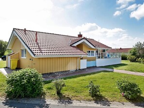 A two-story residential building with a tiled roof, a visible chimney, and a small porch area.