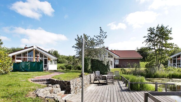 A residential property with a wooden deck, outdoor seating, and a pond. - Holiday Home in Otterndorf (Otterndorf)
