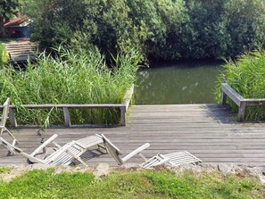 A wooden dock leading to a calm water body, surrounded by lush greenery. - Holiday Home in Otterndorf (Otterndorf)