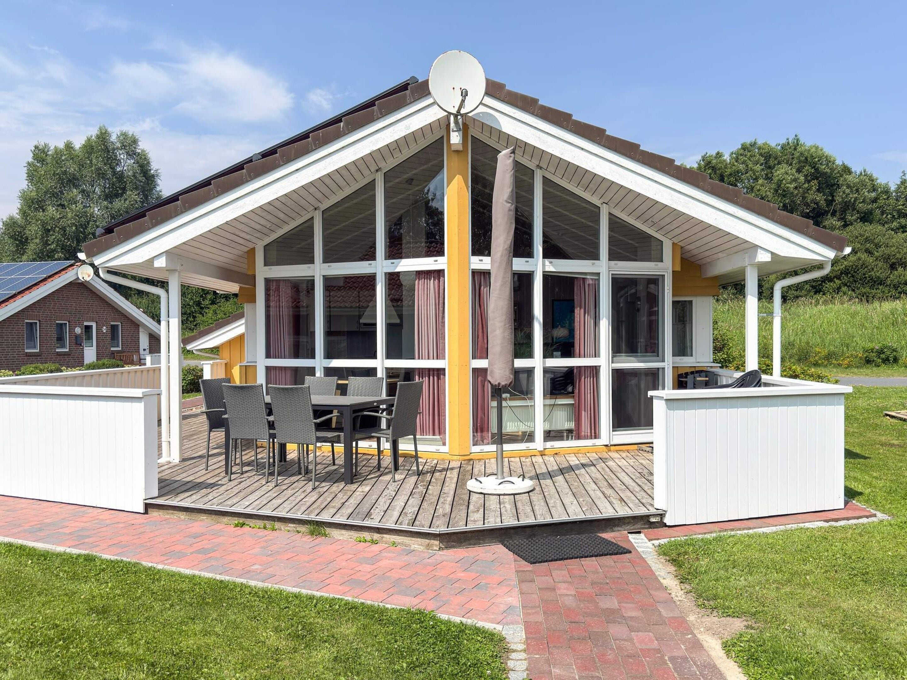 Un espace extérieur abrité, équipé d’une table et de chaises, d’un barbecue et d’une clôture blanche.