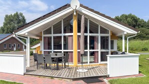 A covered outdoor area with a table and chairs, a barbecue grill, and a satellite dish. - Holiday Home in Otterndorf (Otterndorf)