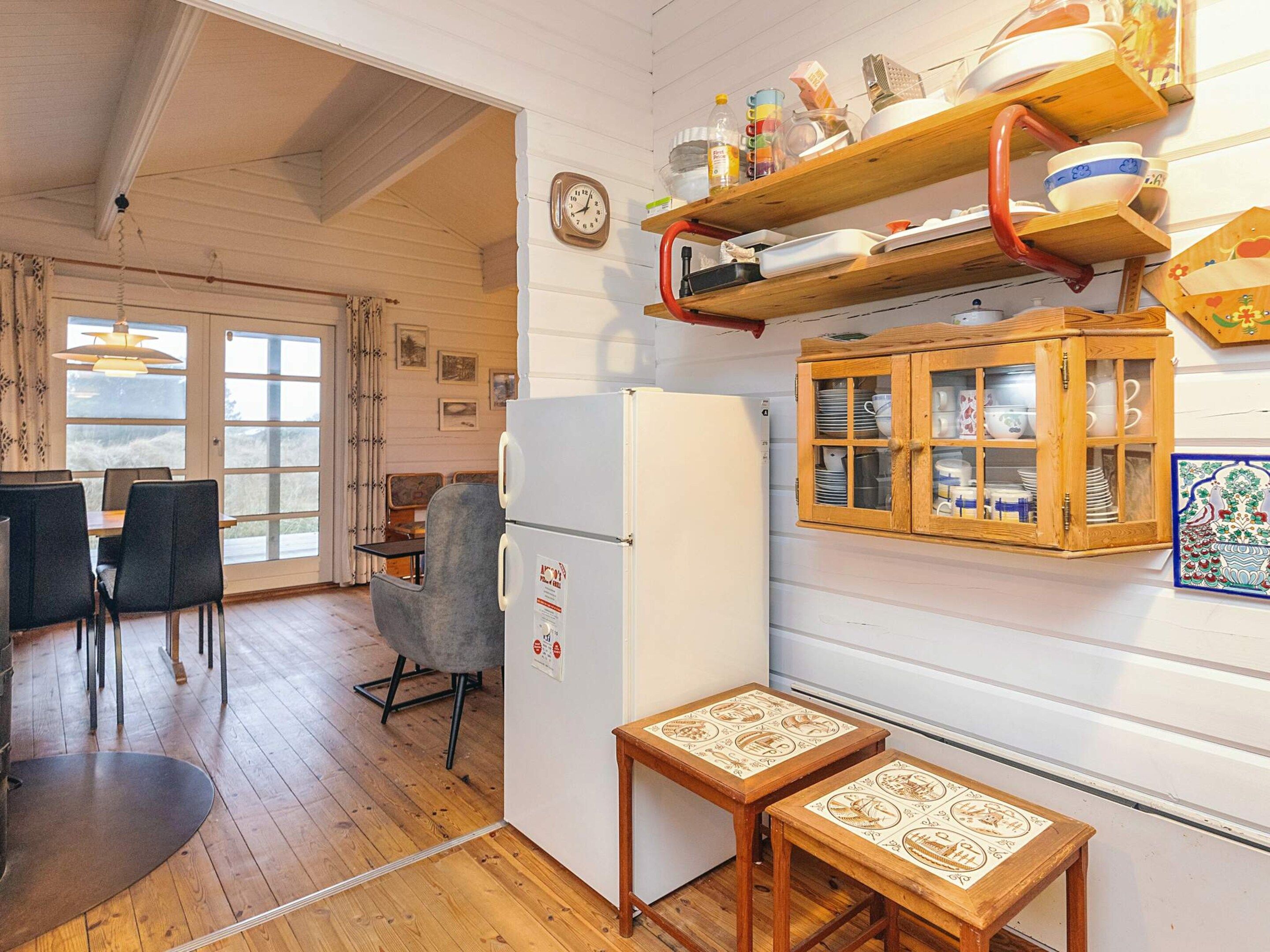 Eine Küche mit Kühlschrank, Holzschränken und einem Essbereich mit Stühlen und Tisch.
