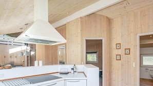 A modern kitchen with wooden paneling, white cabinetry, and a large island with a sink. - Tranquil Retreat With Spa - By Traum Ferienwohnungen (Aalbaek)