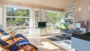 A spacious room with large windows, a television, a green chair, and a sofa. - Tranquil Retreat With Spa - By Traum Ferienwohnungen (Aalbaek)