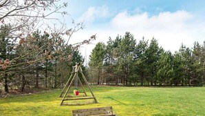 A swing set in a grassy field with trees in the background. - Peaceful Holiday Home in Jutland with Hot Tub (Oksbol)
