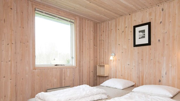 A room with wooden walls, two beds with white bedding, a window with blinds, a wall-mounted light, and a framed picture. - Peaceful Holiday Home in Jutland with Hot Tub (Oksbol)