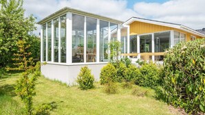 A modern house with a large glass conservatory, surrounded by lush greenery and a well-maintained lawn. - 6 Person Holiday Home in Hejls (Hejls)