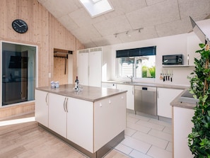 A modern kitchen with a central island, built-in appliances, and a large window providing natural light. - Quaint Holiday Home in Fur Jutland near Fjord (Glesborg)