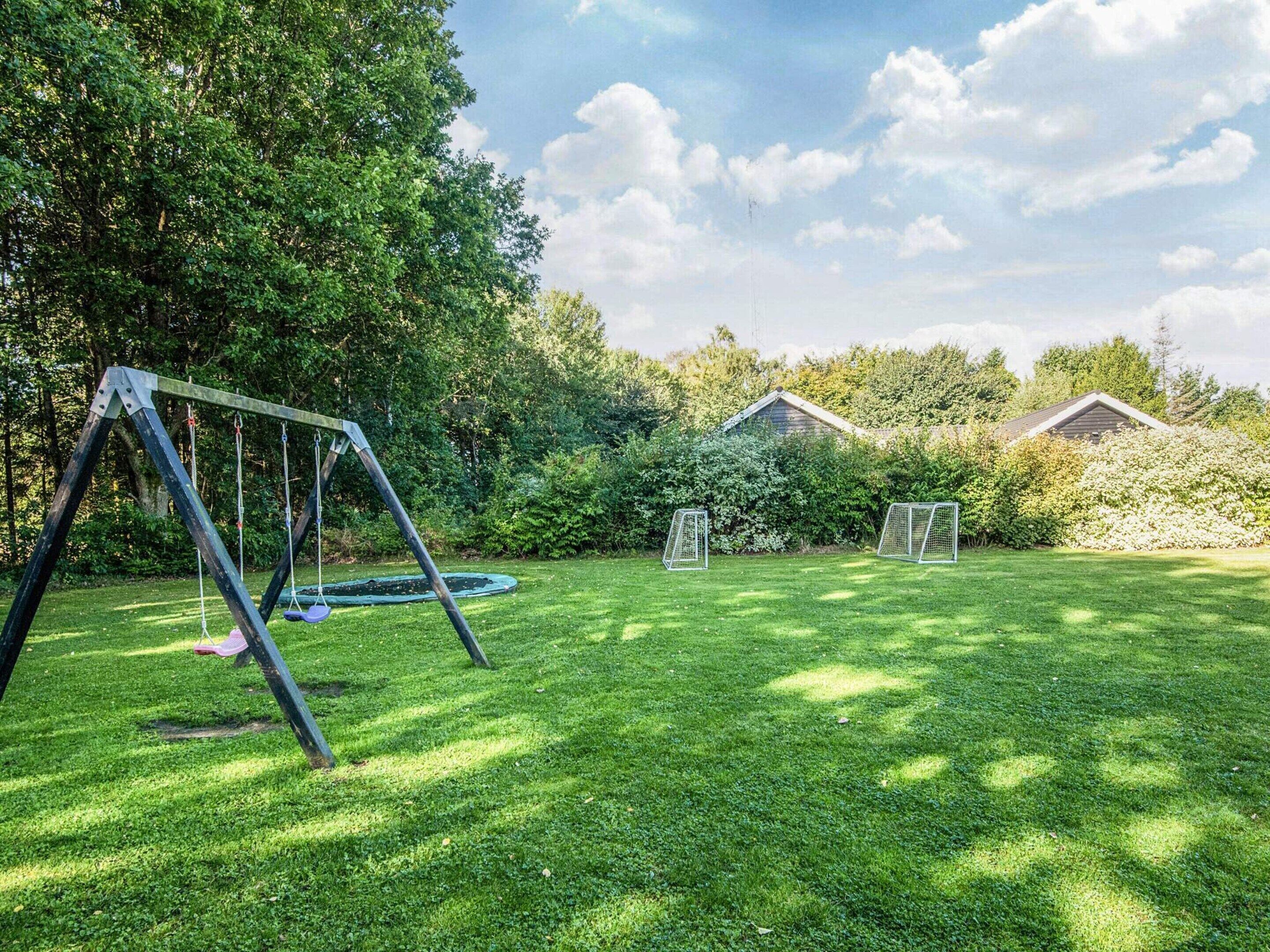 A backyard with a swing set, a trampoline, and two soccer goals.