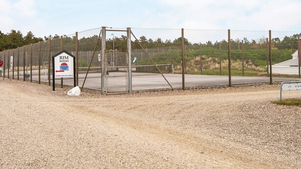 Een omheind gebied met een bord waarop 'RIM ROMO' en 'FORSAMLINGSHUS' staat.