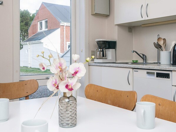 A modern kitchen with white cabinets, a coffee maker, and a dishwasher.