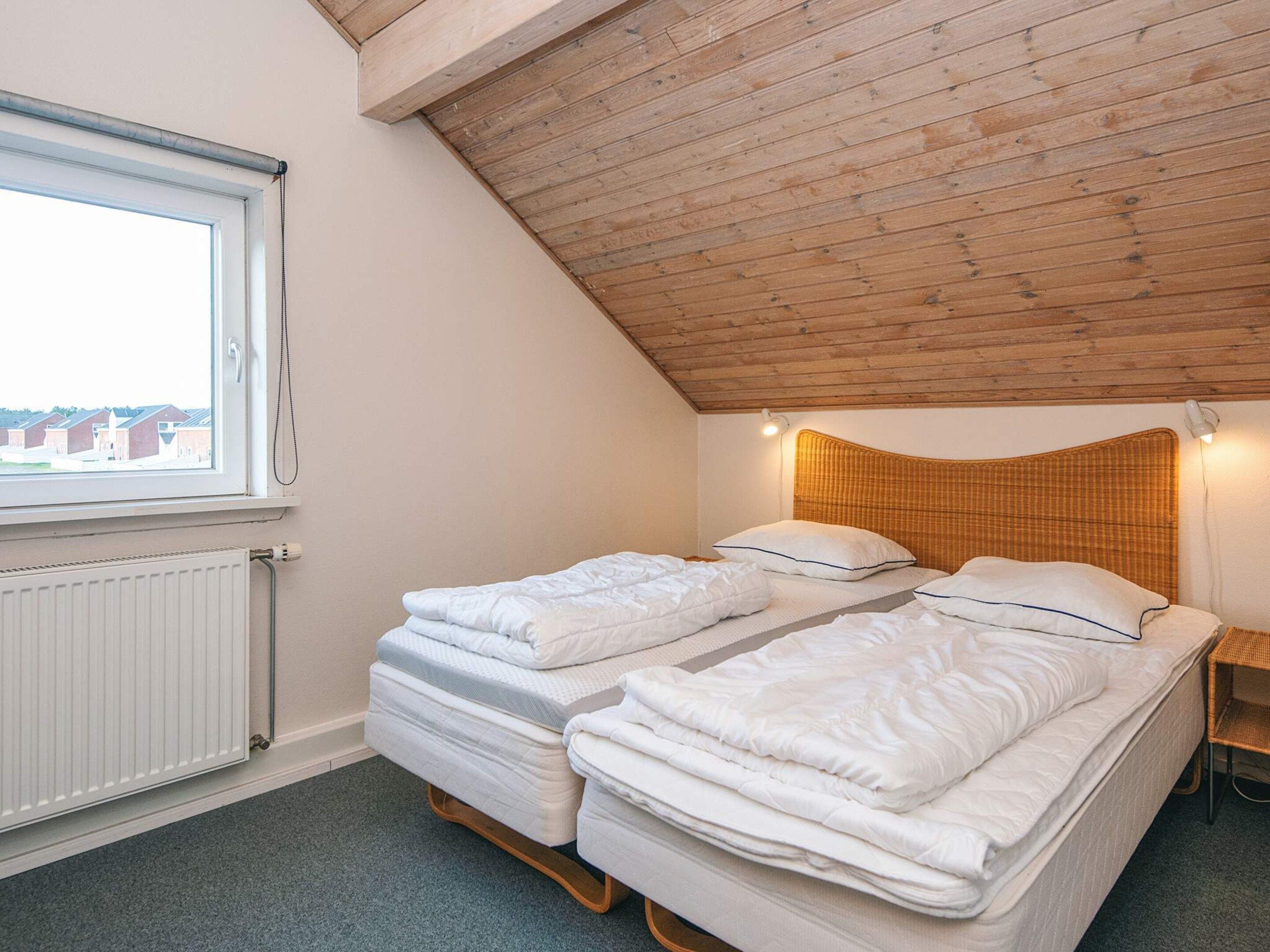 Et lille, hyggeligt værelse med to senge, et vindue og et skråt loft.