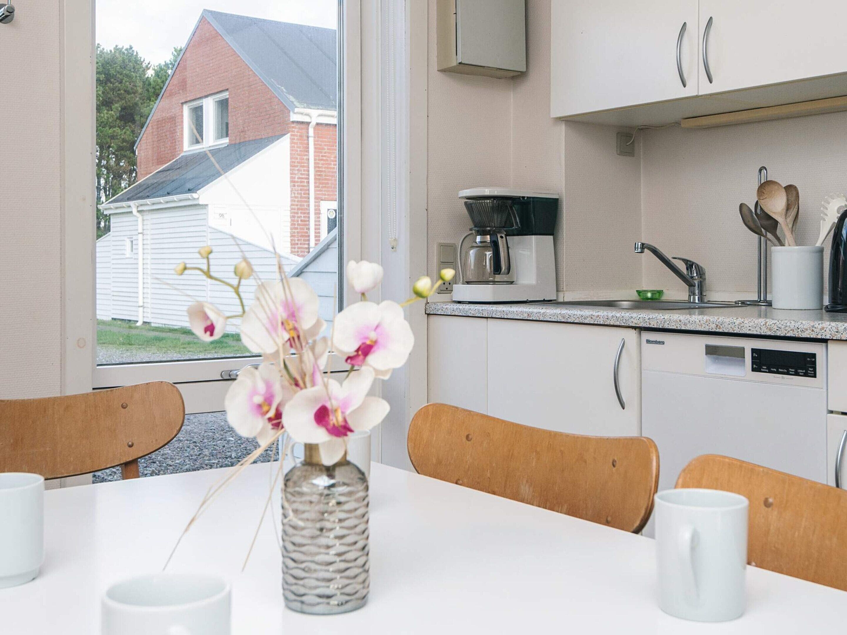 A modern kitchen with white cabinets, a coffee maker, and a dishwasher.