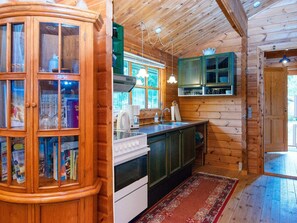 A wooden interior with a kitchen area featuring cabinets, a stove, and a window. - 4 Person Holiday Home in Farvang (Farvang)