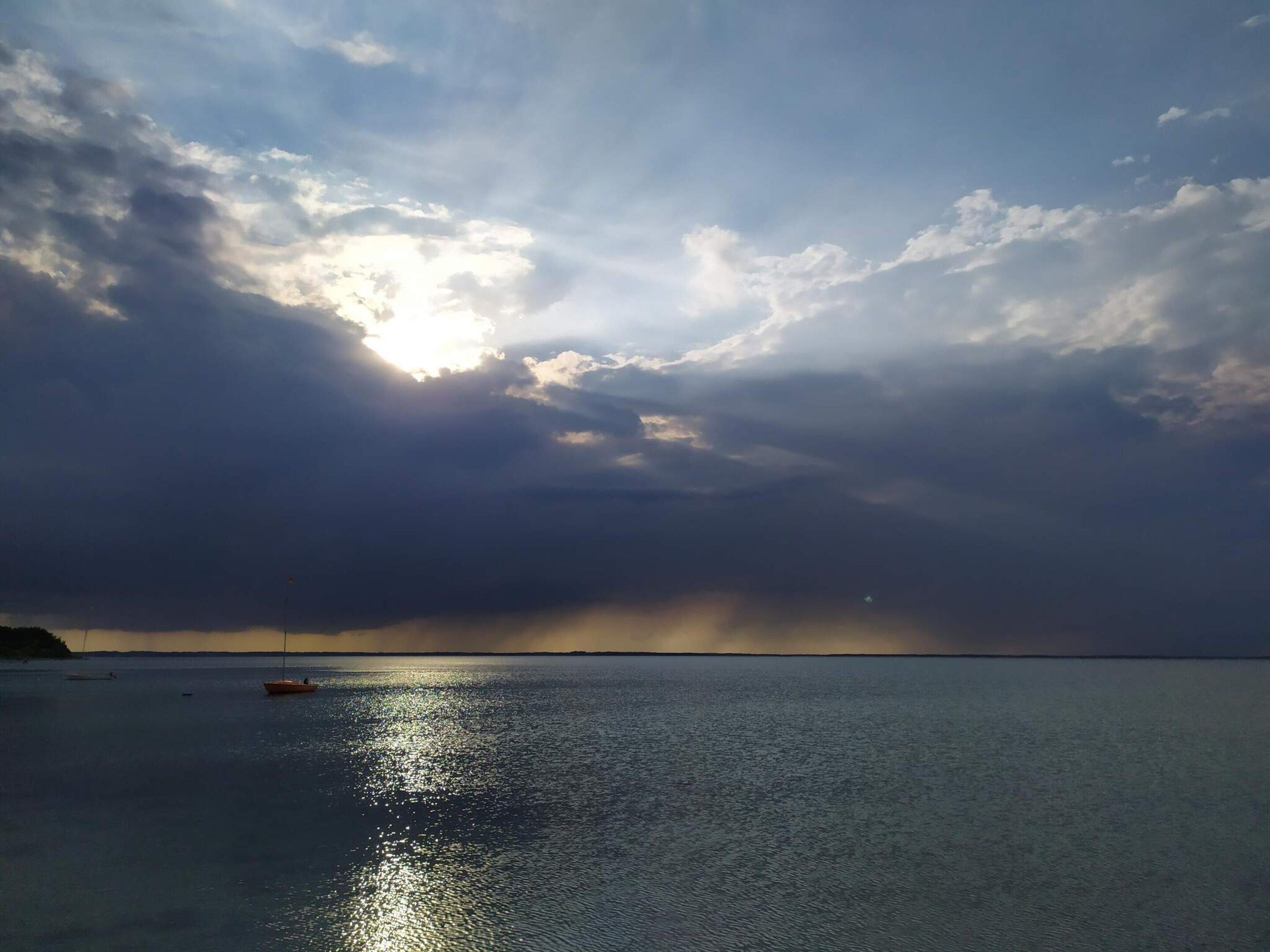 A calm body of water with a boat and a distant shoreline.