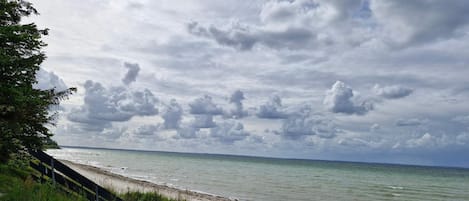 A beach with a grassy foreground and a cloudy sky.
