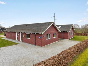 A red building with a gravel driveway and a leaf mulch border. - 5 Star Holiday Home in Nordborg (Nordborg)