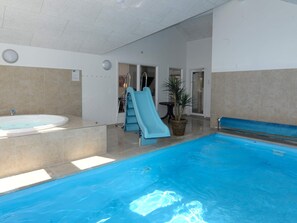 An indoor swimming pool with a slide, a hot tub, and a potted plant. - 5 Star Holiday Home in Nordborg (Nordborg)