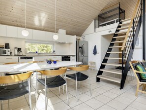 A modern kitchen with white cabinets, a dining table, and a staircase.