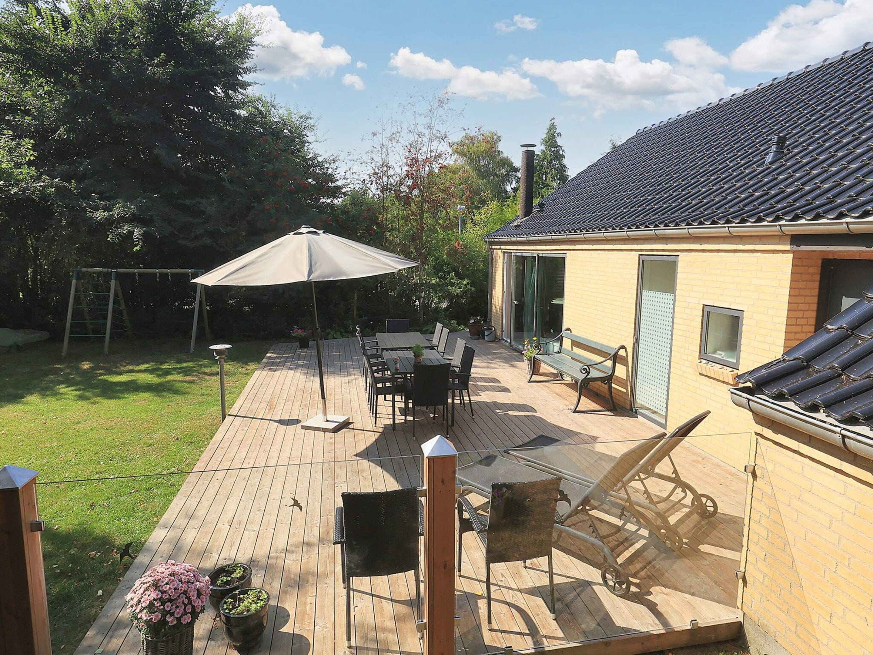 A wooden deck with outdoor furniture, a pergola, and a covered seating area.