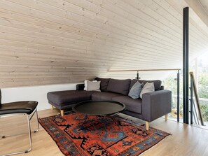 Una sala de estar moderna con un sofá seccional gris oscuro, una mesa de centro redonda y una alfombra estampada.