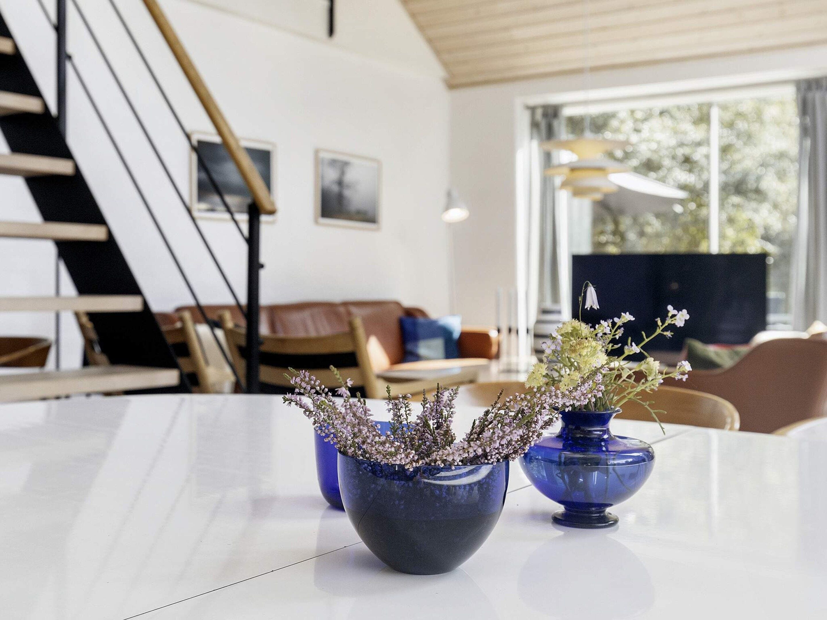 Un interior moderno con una escalera, un comedor y un ventanal con vistas.