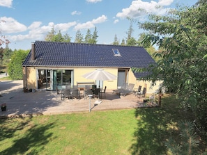 A house with a tiled roof, a patio with outdoor furniture, and a large sliding glass door. - 4 Star Holiday Home in Vaeggerlose (Vaeggerlose)