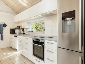 A modern kitchen with white cabinetry, stainless steel appliances, and a window providing natural light.