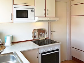 A compact kitchen with a microwave, stove, and a coffee maker.
